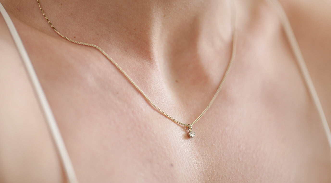 Closeup picture of a womans neck that has a moissanite diamond necklace