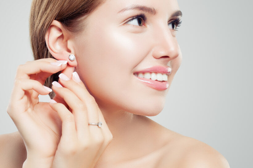 Woman putting on Moissanite Diamond earrings